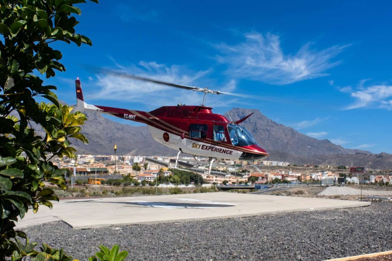 Red helicopter taking off for a Tenerife helicopter tour from the Adeje heliport.