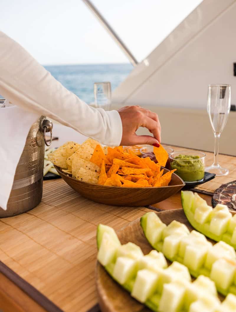 Guests reaching for nachos, dips and melon with champagne on the Tigresa yacht in Tenerife by Club Canary