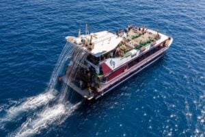 Aerial view of a glass bottom whale watching boat cruising across the Atlantic Ocean with passengers enjoying a sightseeing tour in Tenerife.
