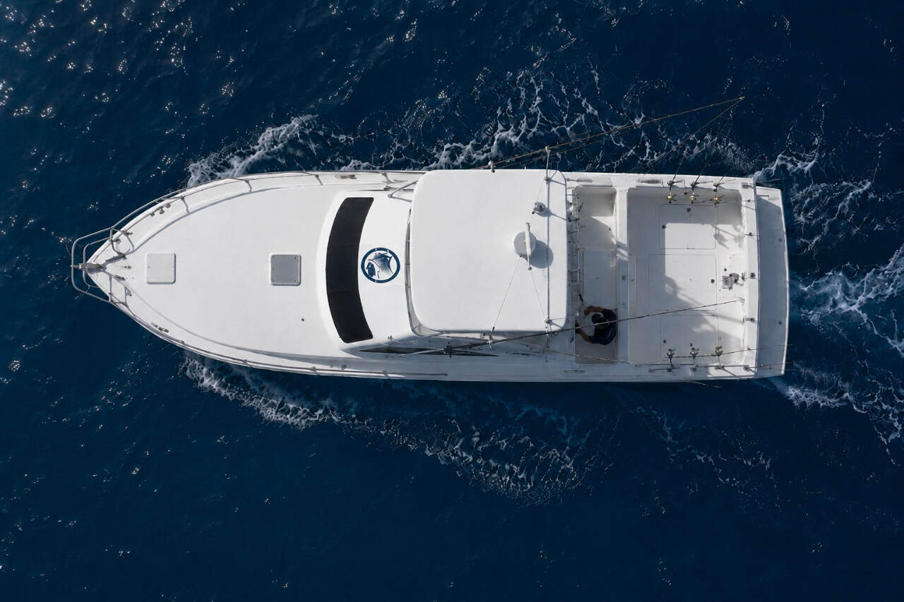 Top-down aerial view of the White Marlin fishing charter boat travelling through deep blue waters in Gran Canaria.