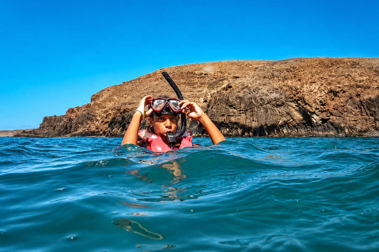 Young snorkeler wearing a mask and life vest floating in the crystal-clear waters of Costa Calma, Fuerteventura, before exploring the reef.