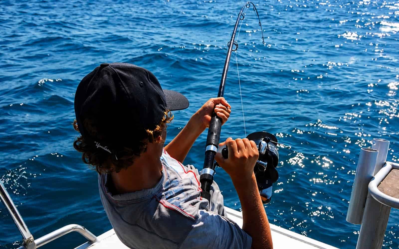 Guest fighting a fish with a bent rod on a boat in Lanzarote