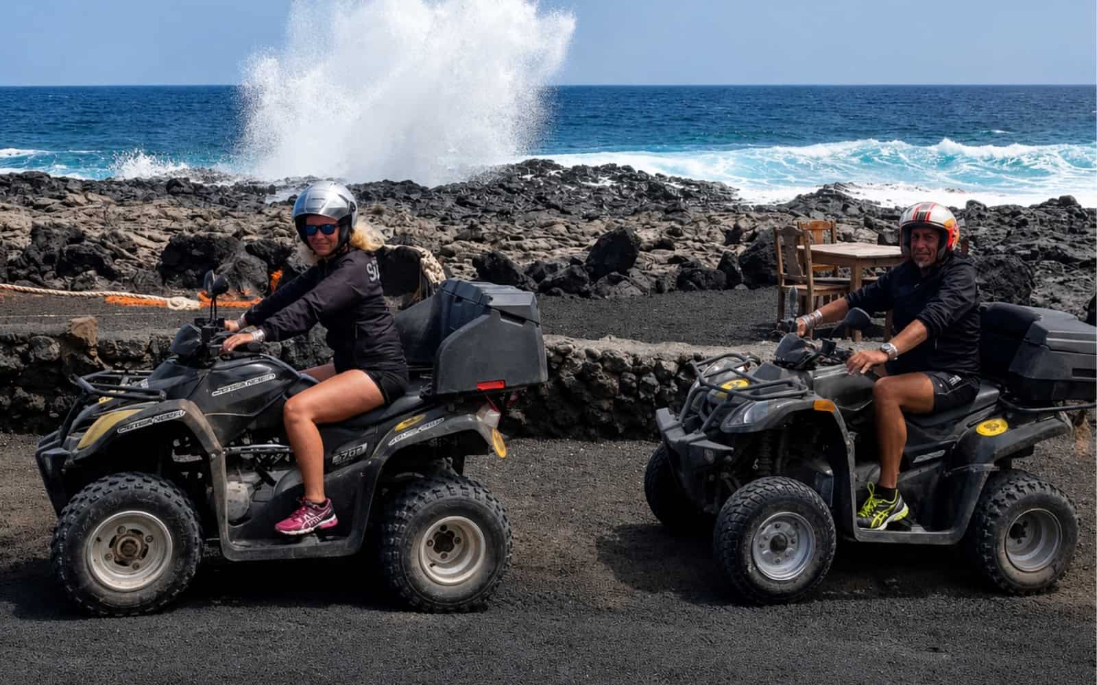 Two riders on quads beside the volcanic coast of Lanzarote