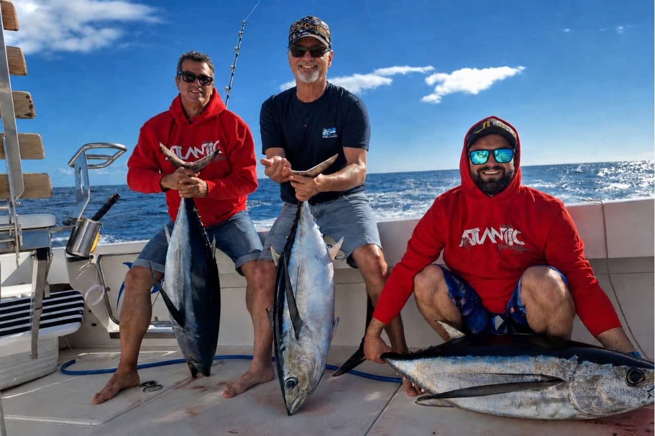 Three anglers posing with freshly caught tuna during a big game fishing trip in Fuerteventura