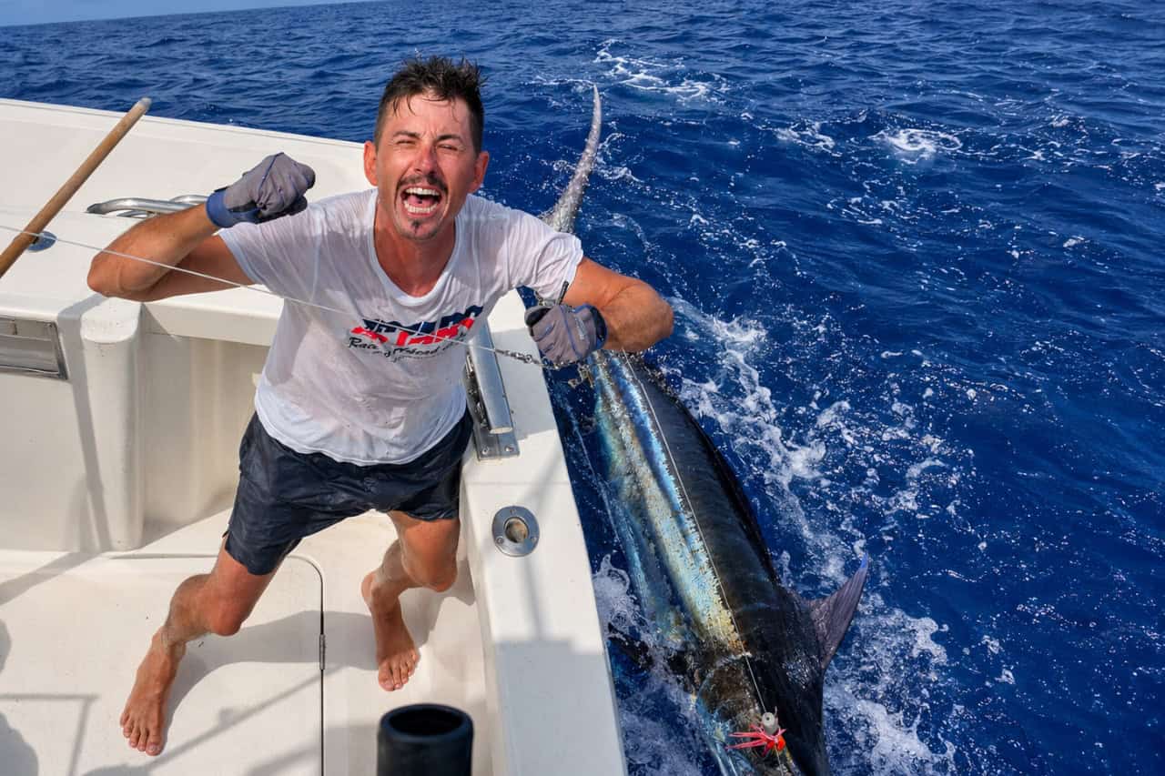 Angler celebrating beside a large marlin during a big game fishing trip in Tenerife.