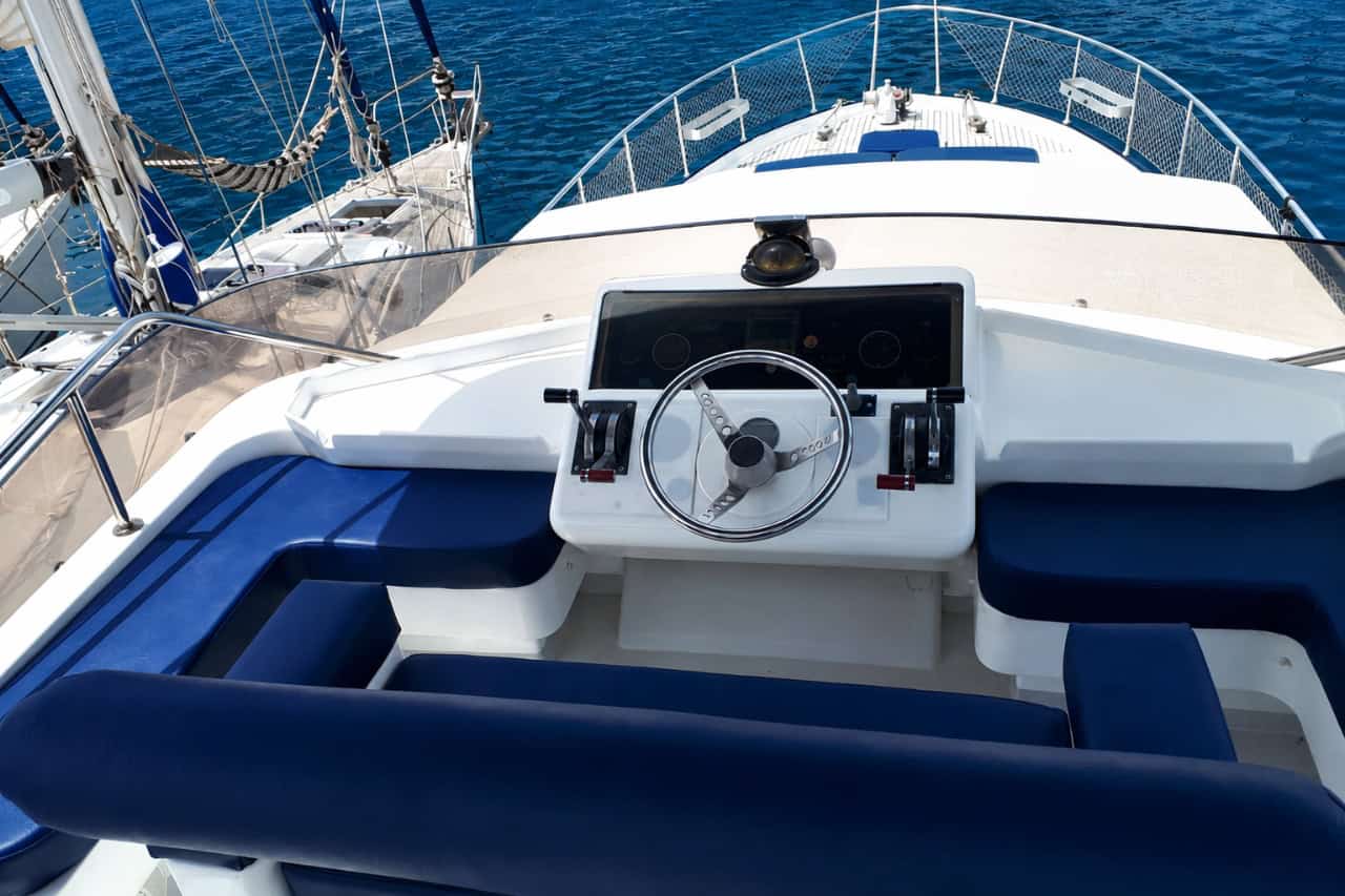 Upper helm and steering area of the Blue M private yacht in Gran Canaria, with blue seating and views over the bow and ocean.