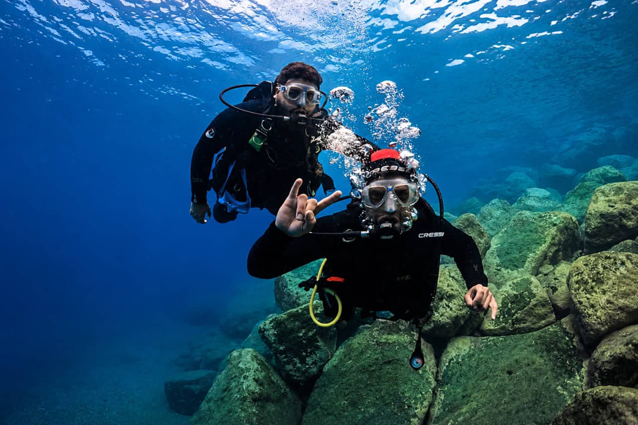 Two beginner divers on a try dive in the clear water of Puerto de Mogan Gran Canaria
