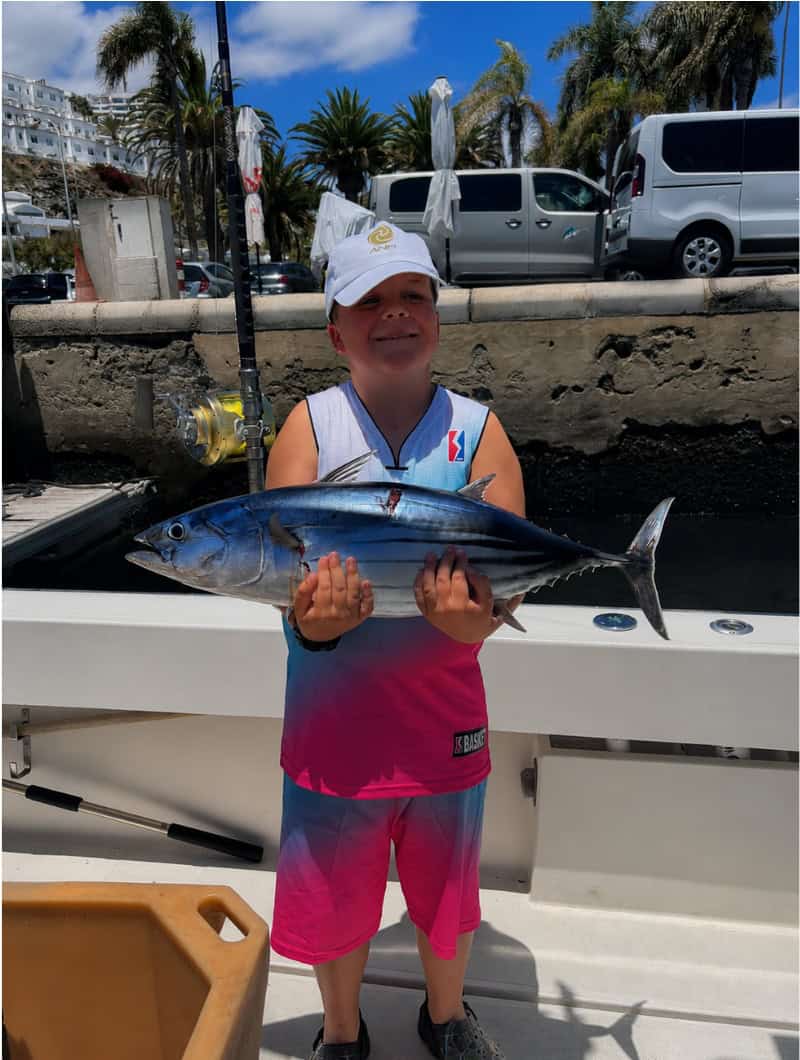 Young guest holding a fish during a family fishing trip in Gran Canaria from Puerto Rico
