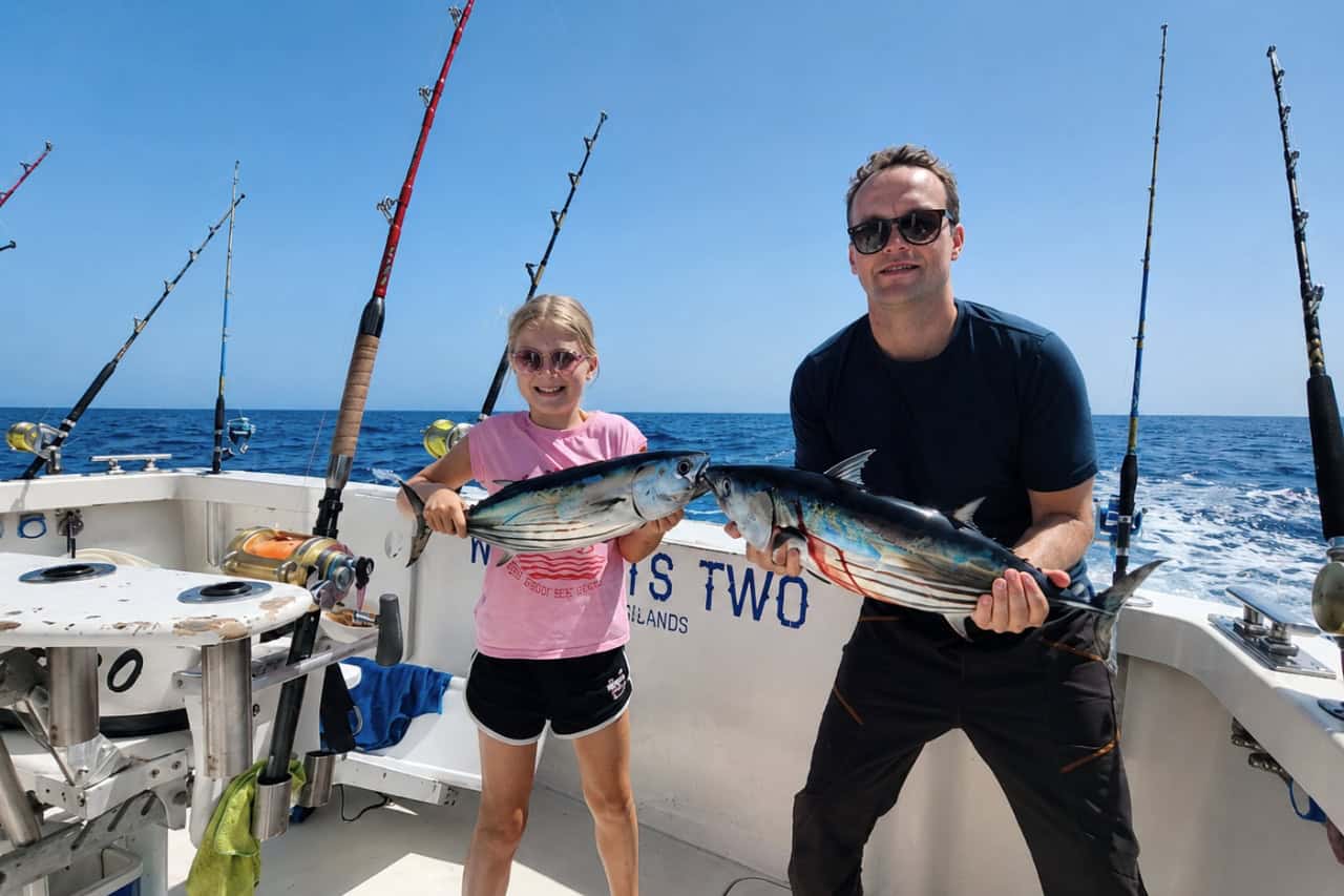 Father and daughter holding freshly caught tuna during a family fishing trip off the coast of Tenerife.