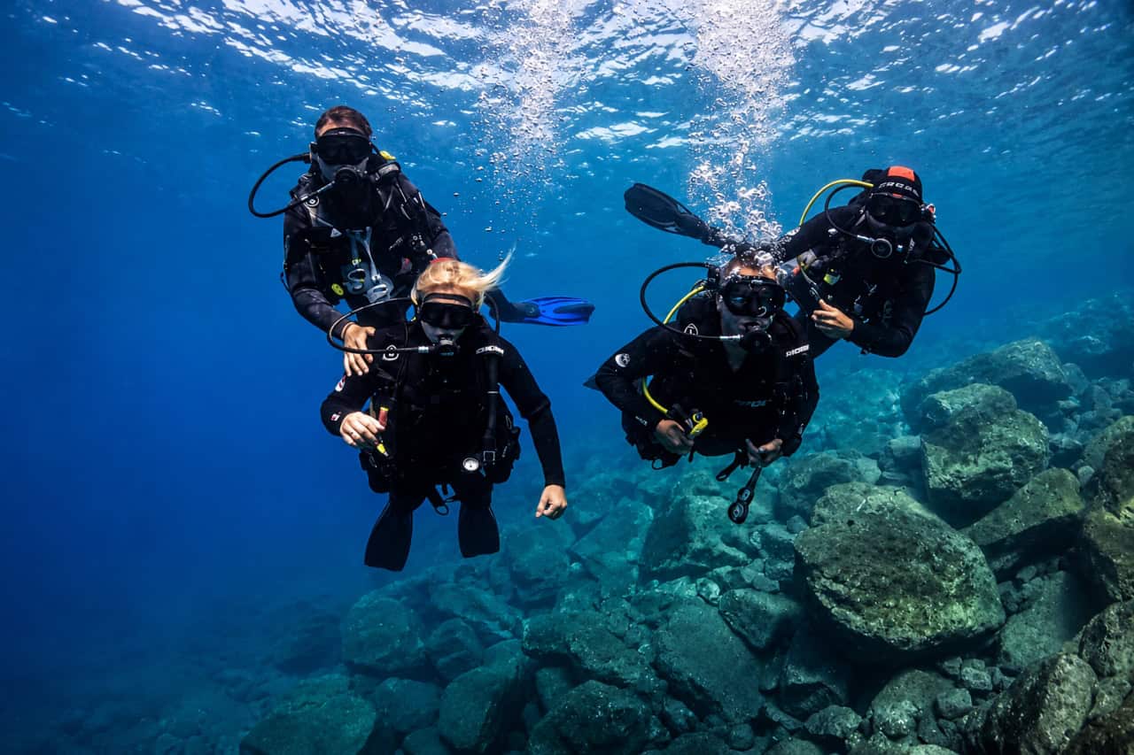 Guided scuba lesson in Gran Canaria with new divers building confidence underwater beside a rocky volcanic reef.