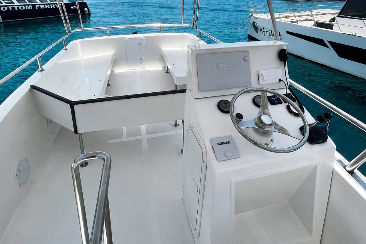 Modern white boat helm with steering wheel, navigation equipment and spacious seating in a Gran Canaria marina.