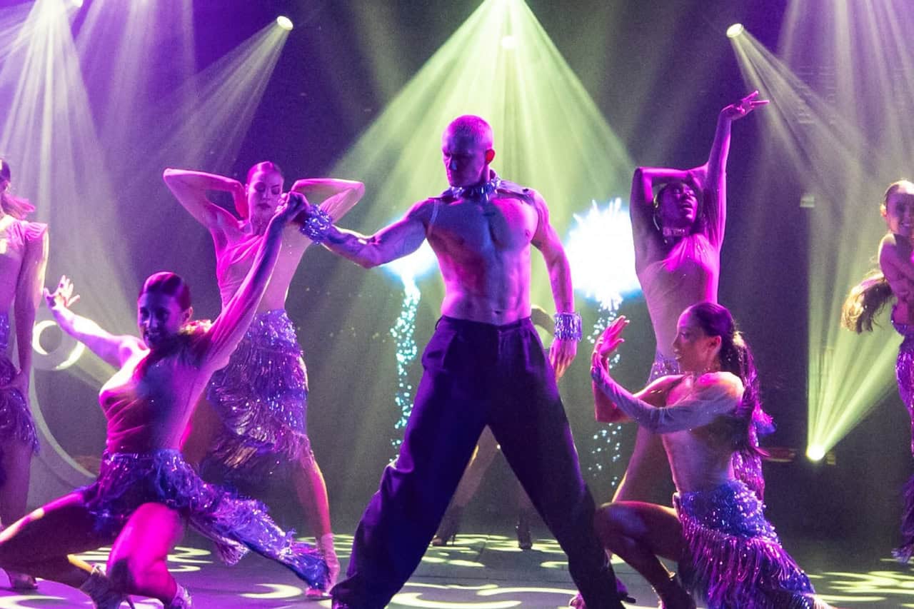 Live dancers performing under colourful stage lights during a Gran Canaria dinner show.