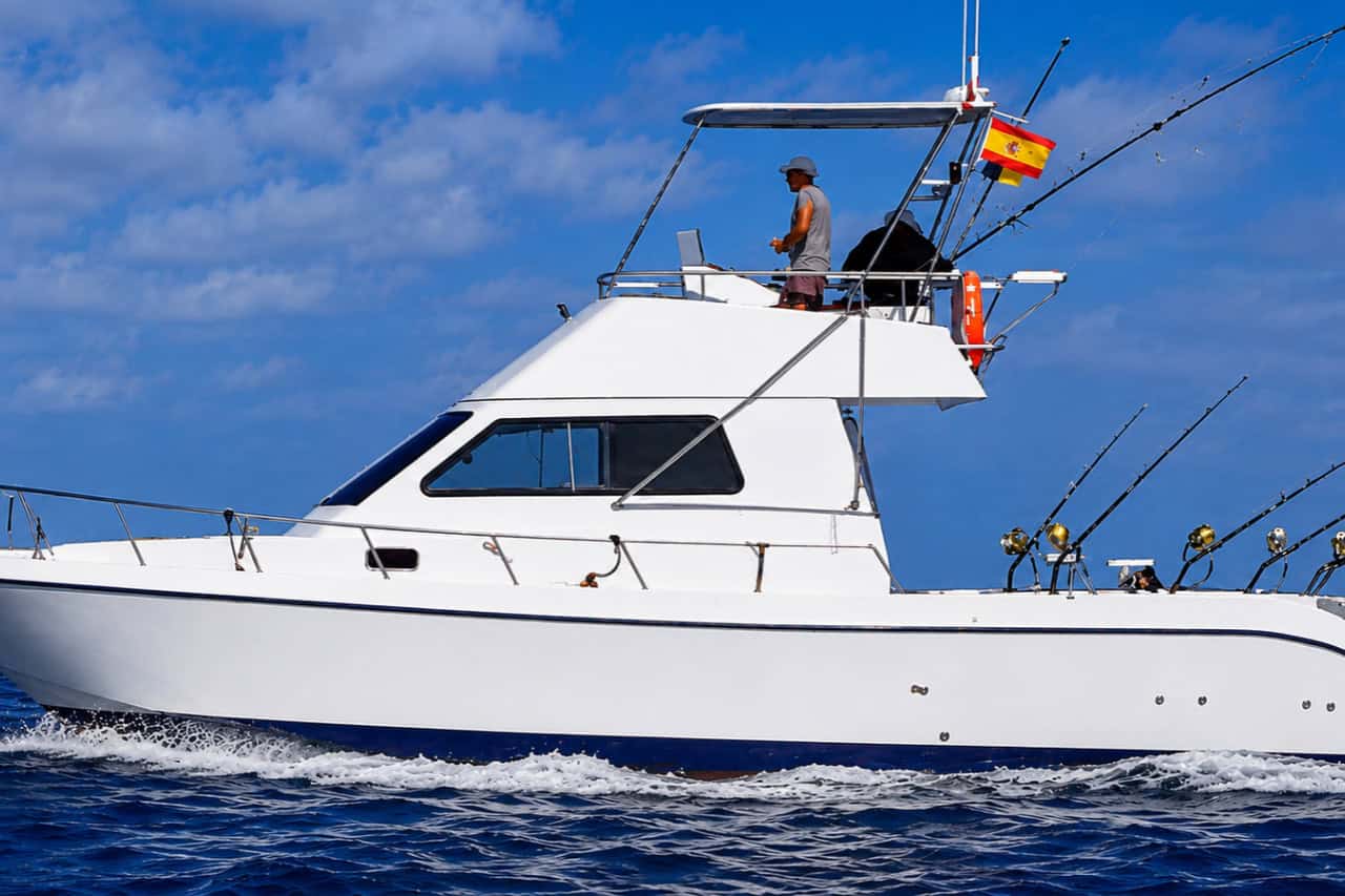 Sportvisboot varend voor de kust van Gran Canaria met meerdere vishengels klaar voor een dag op de Atlantische Oceaan