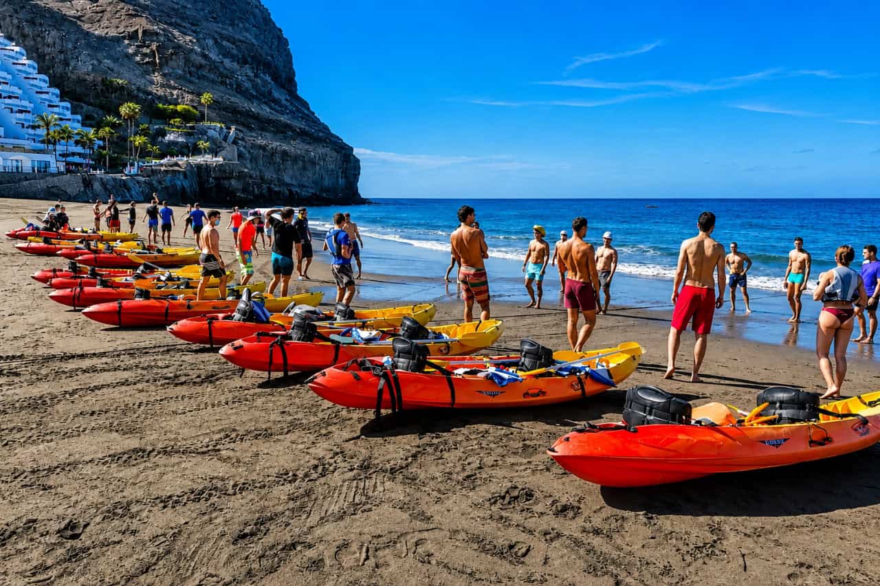 Colorful kayaks lined up on a Gran Canaria beach as guests prepare for a guided sea kayaking tour along the coast.