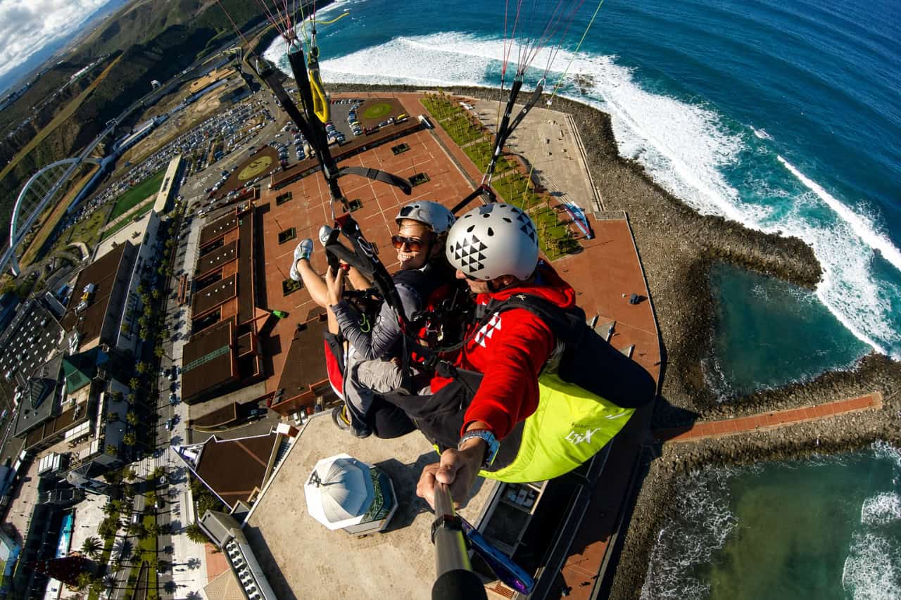 Tandem-Gleitschirmfliegen auf Gran Canaria mit einem Fluglehrer und Passagier hoch über der Atlantikküste und dem Strand.