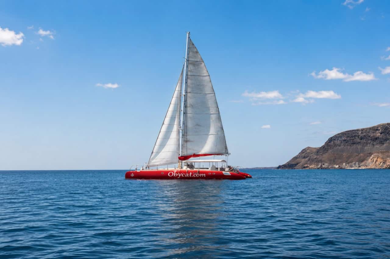 Catamarán de lujo ObyCat navegando por la costa de Gran Canaria durante un alquiler de catamarán privado.