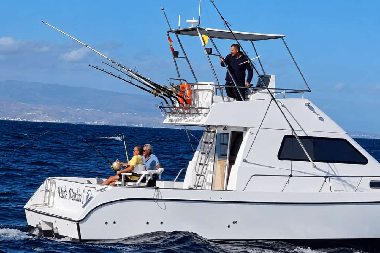Guests fishing from a sport fishing boat in the Atlantic with the Gran Canaria coastline behind