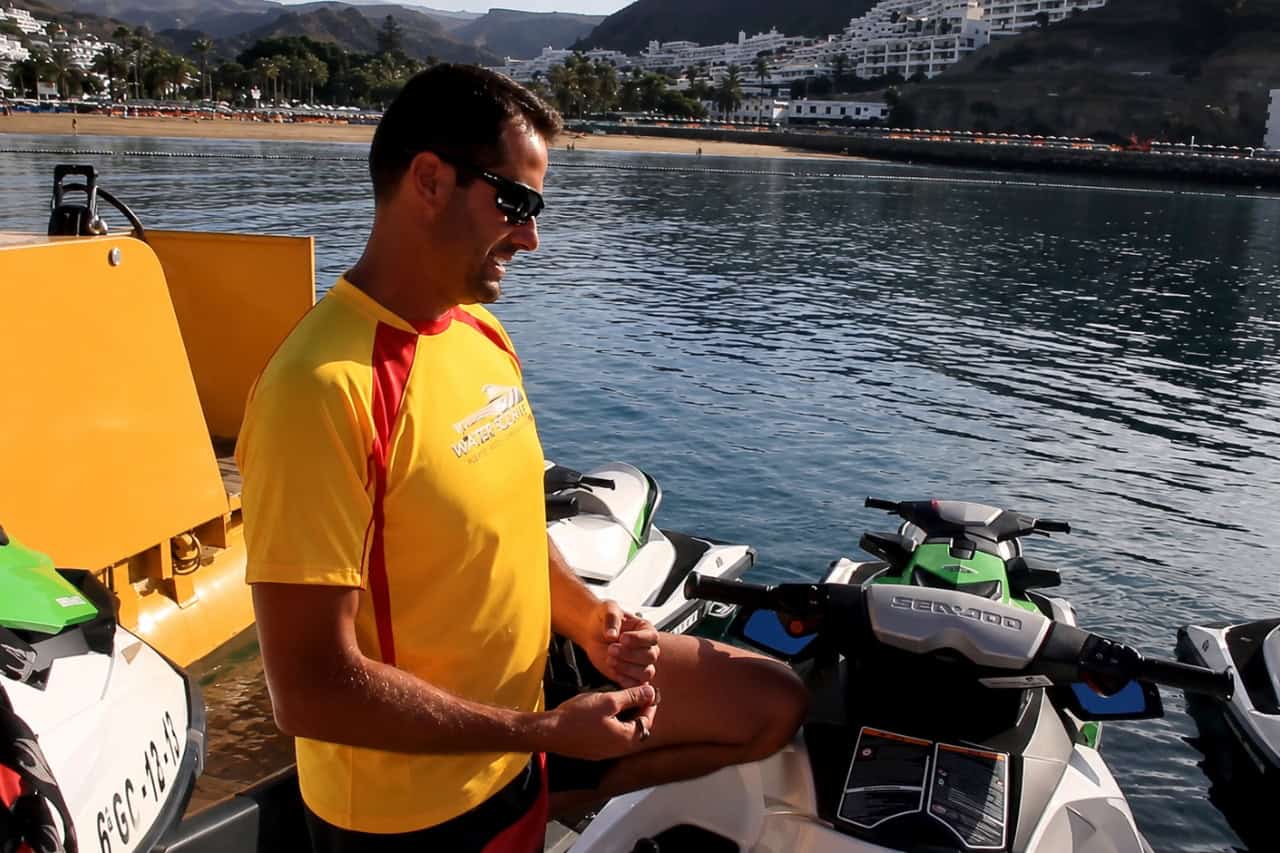 Instructor de deportes acuáticos impartiendo una charla sobre seguridad en motos acuáticas junto a las motos acuáticas Sea-Doo en un puerto deportivo de Gran Canaria.