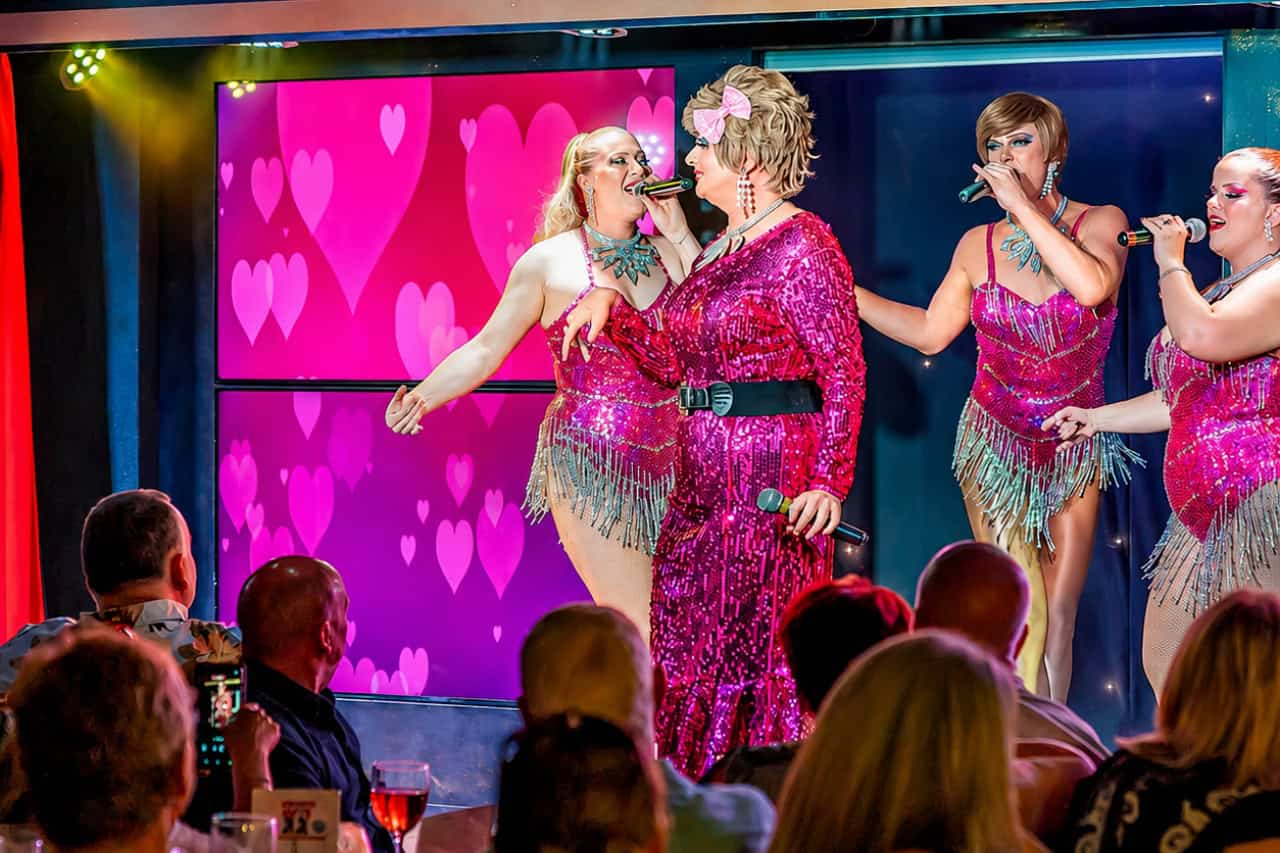 Drag performers in pink costumes during the live musical comedy show