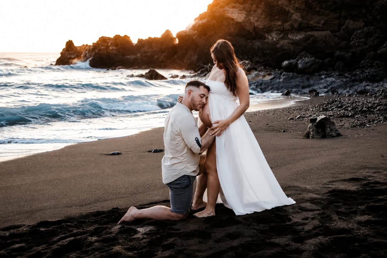 Paar während eines romantischen Babybauch-Shootings an einem schwarzsandigen Strand