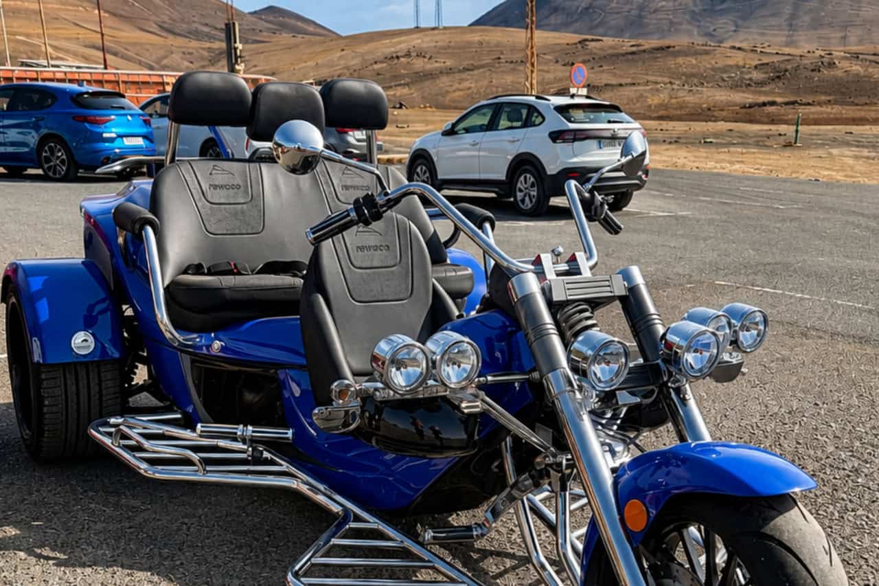 Blue Rewaco trike parked in Lanzarote with volcanic mountains in the background, ready for a guided trike tour across the island's unique landscapes.
