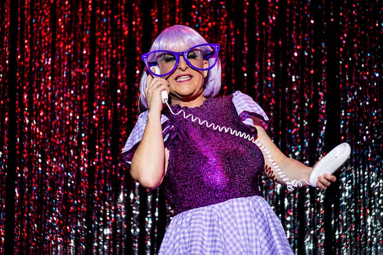 Comedy drag performer on stage at Music Hall Tavern Gran Canaria wearing a colourful purple costume during the live show.