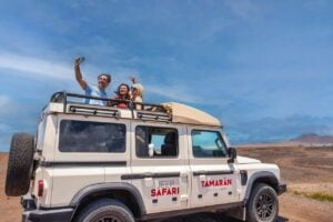 Tres personas haciéndose un selfi desde un jeep 4x4 descapotable mientras exploran los paisajes volcánicos todoterreno de Fuerteventura.