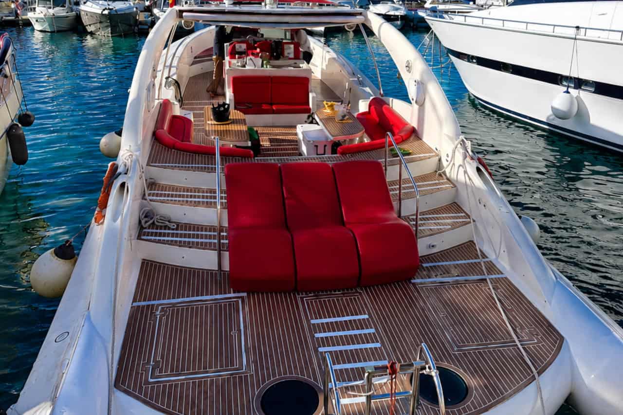 Ruim Opera 60-terras op Tenerife met rode zitplaatsen, tafels en uitzicht op de jachthaven in Puerto Colón.