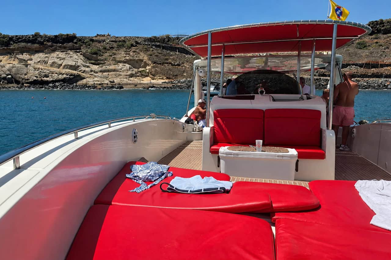 Rode zitplaatsen op het zonnedek tijdens de boottocht Opera 60 op Tenerife, vlakbij de rotsachtige kust.