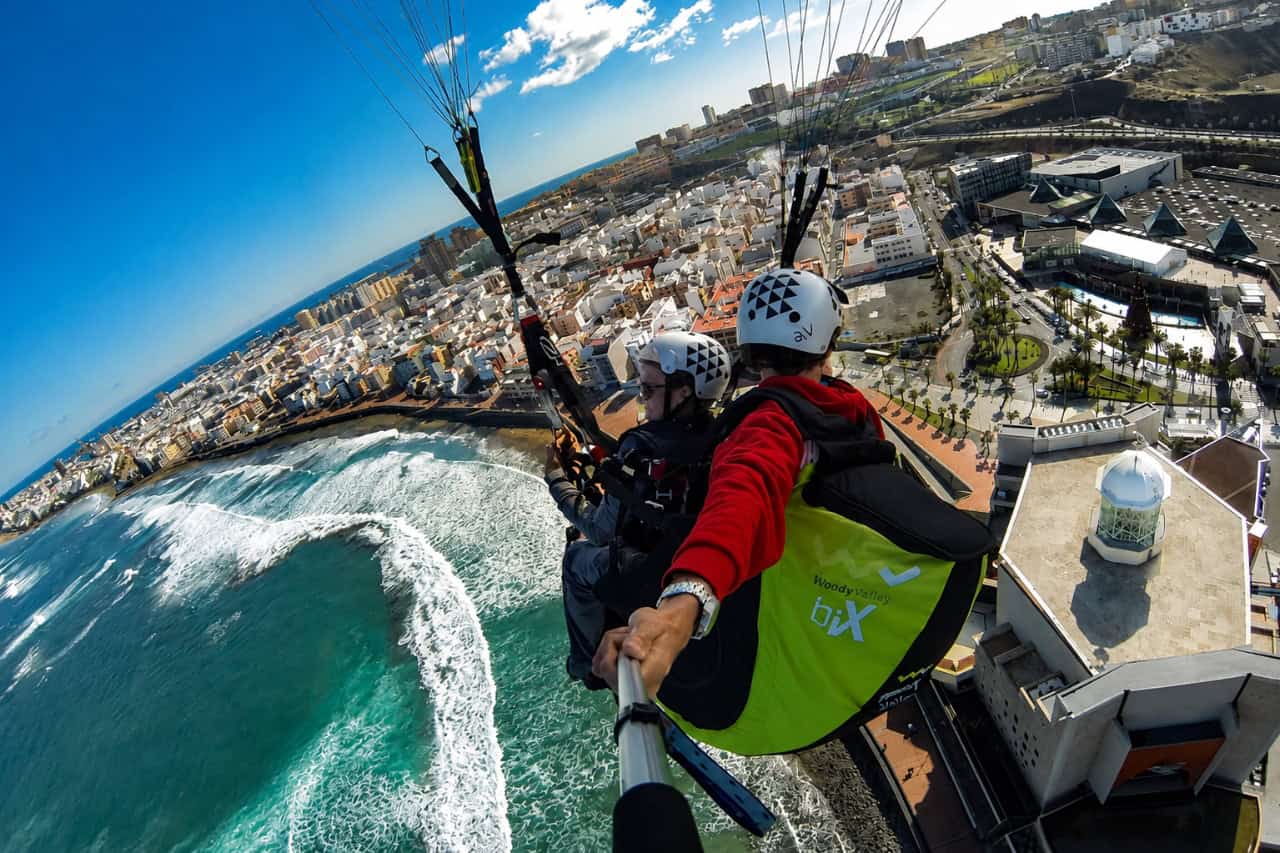 Tandem-Gleitschirmfliegen auf Gran Canaria mit einem Fluglehrer und Passagier hoch über der Atlantikküste und dem Strand.