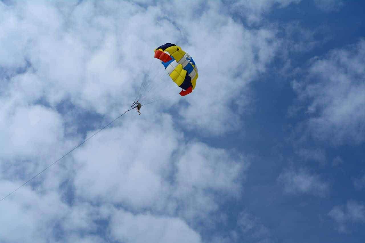 Solo parasailing experience under a colourful parachute high in the cloudy blue sky over Gran Canaria.