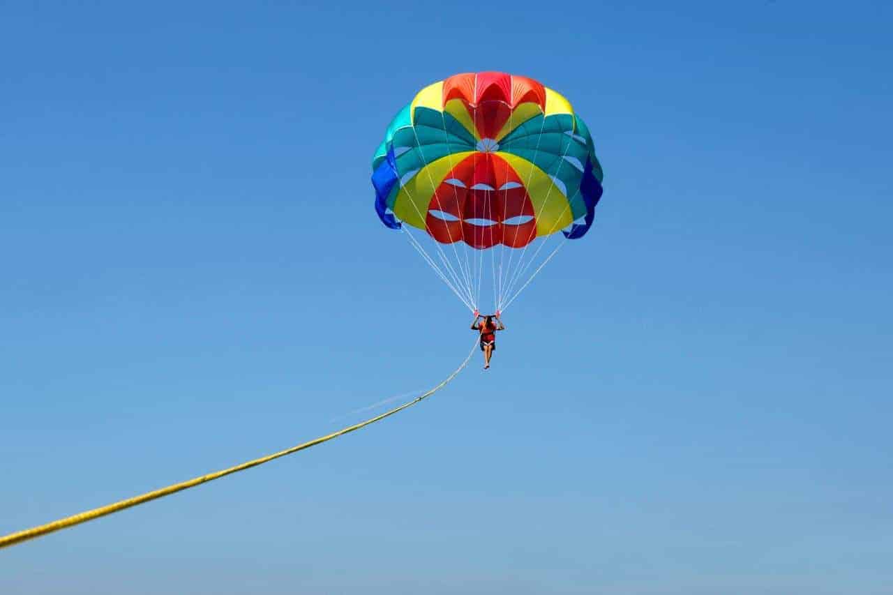 Solo parasailing experience under a colourful parachute high in the cloudy blue sky over Gran Canaria.