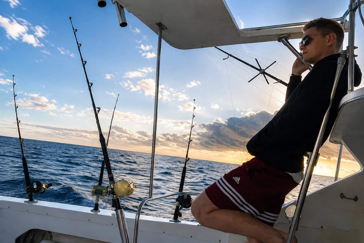 : Guest relaxing beside professional fishing rods during a private sunset fishing charter in Tenerife.