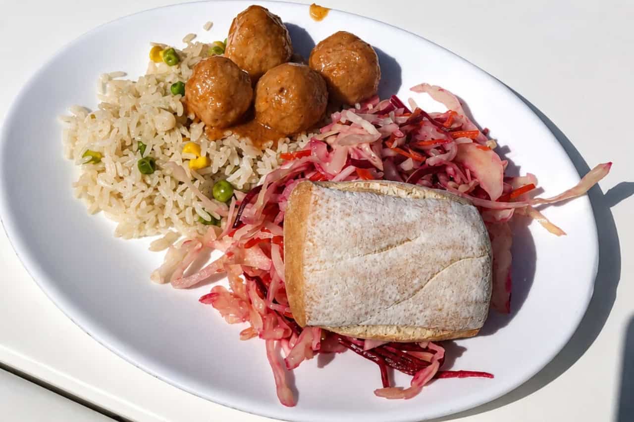 Déjeuner servi à bord lors de l'excursion en bateau Royal Delfin à Tenerife, comprenant du riz, des boulettes de viande, de la salade et du pain.