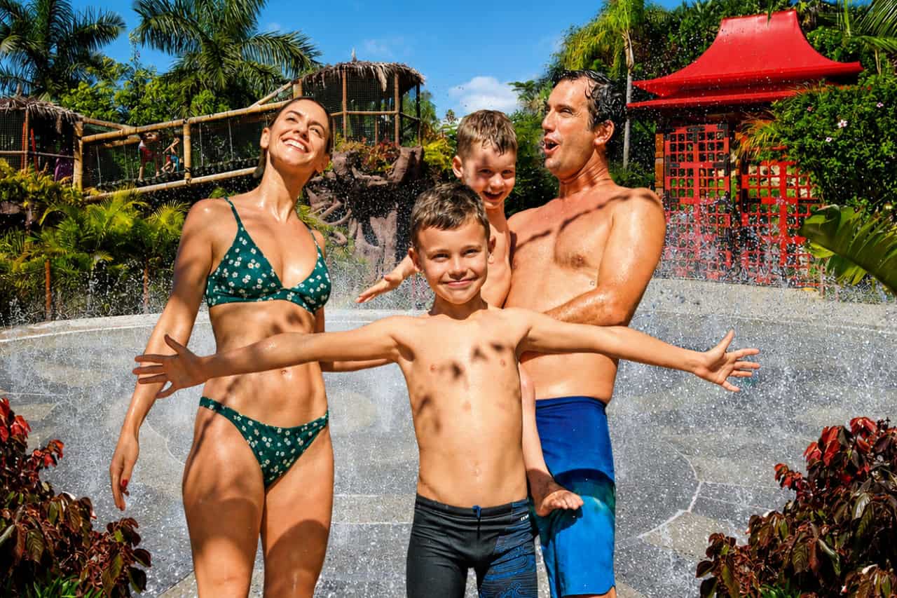 Ģimene ar diviem bērniem bauda strūklakas Siam Park parkā