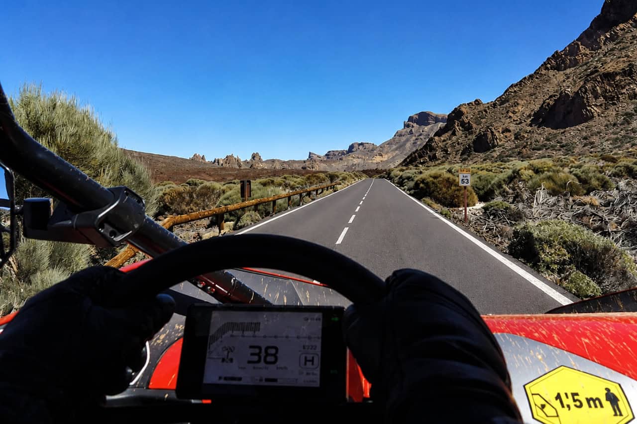 Driver’s view from a red buggy travelling along a smooth volcanic road through the dramatic landscape of Teide National Park.