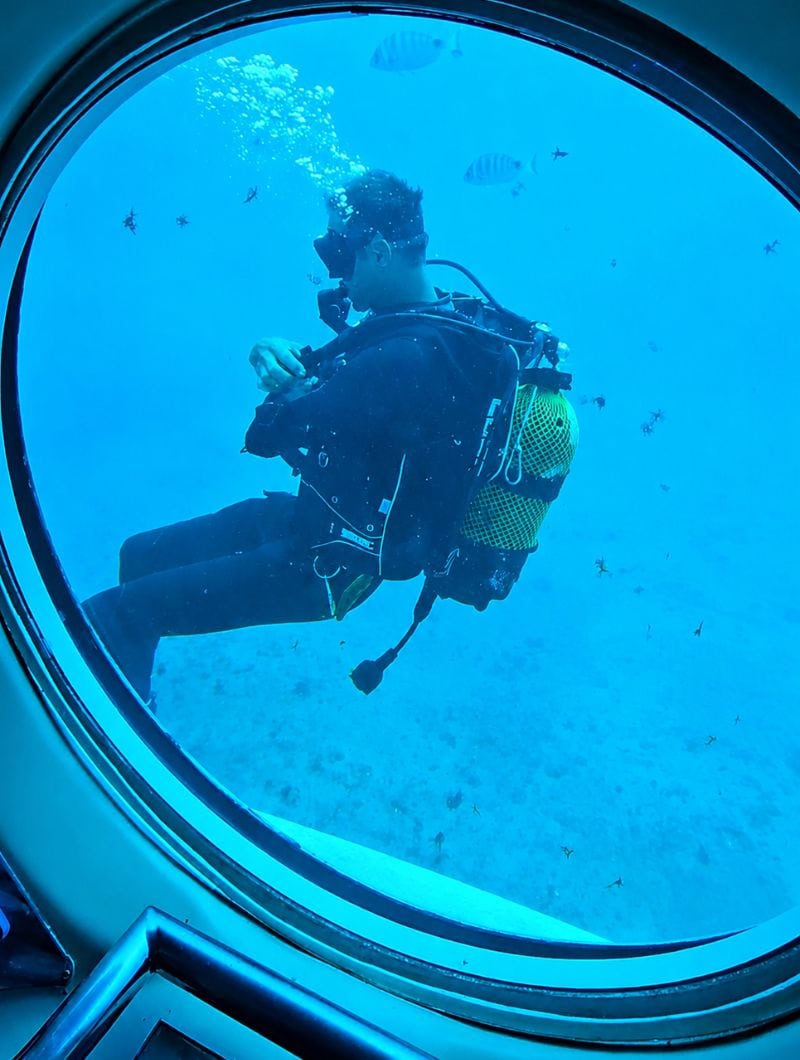 Ein Taucher, gesehen durch ein rundes Passagierfenster auf der U-Boot-Tour auf Teneriffa
