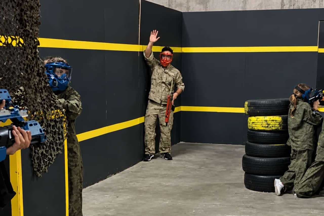Players in protective gear using tyre cover during an airsoft game in Tenerife
