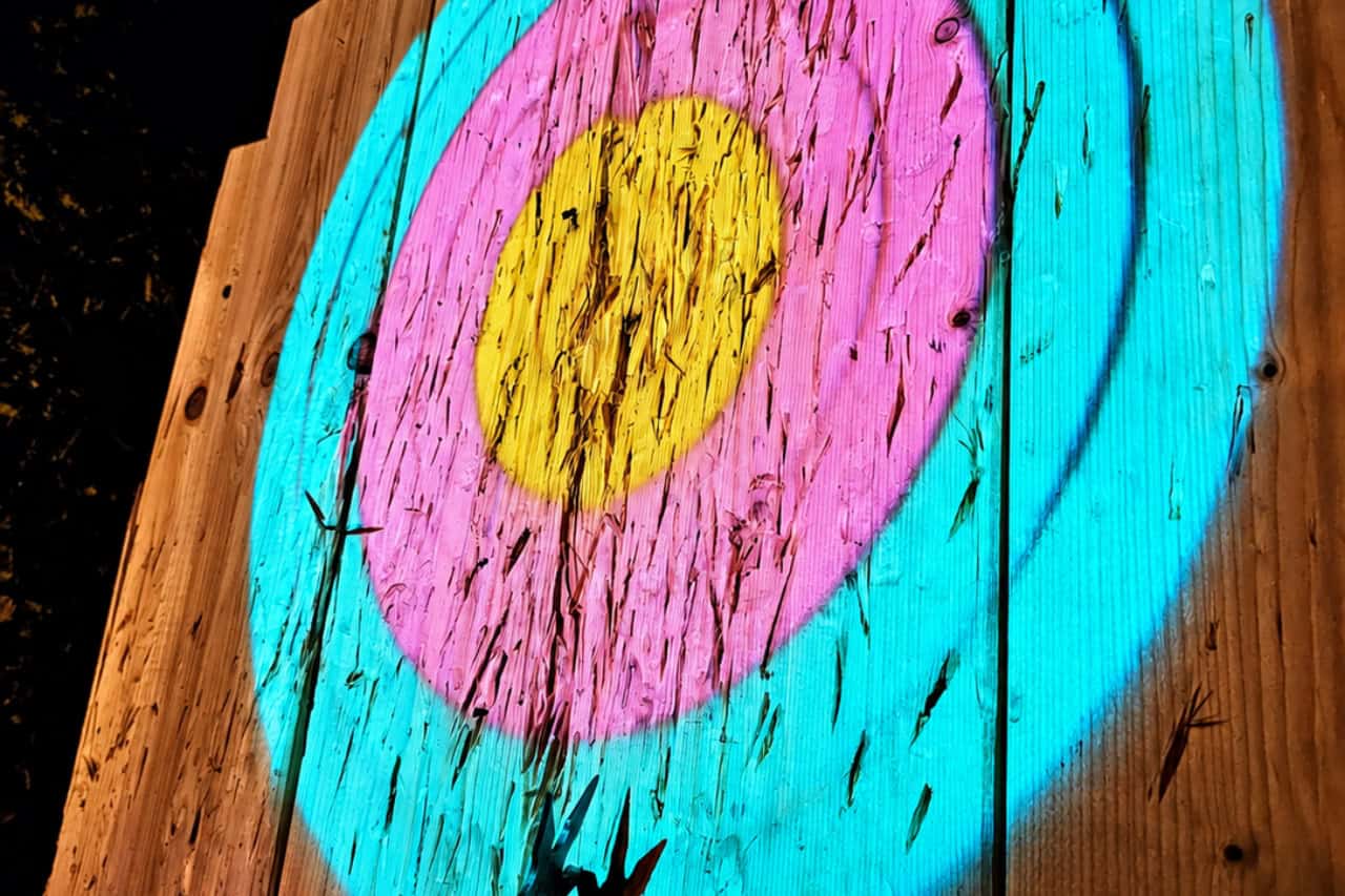 Colorful illuminated wooden target with throwing stars during the indoor axe throwing experience in Playa de Las Américas, Tenerife.