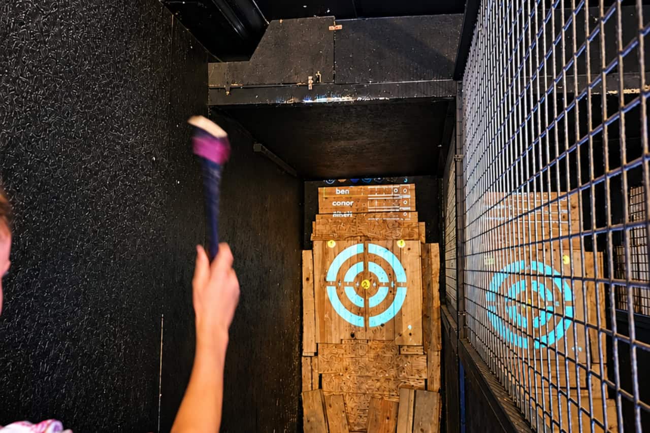Guest throwing an axe at an interactive target inside the indoor axe throwing arena in Playa de Las Américas, Tenerife.