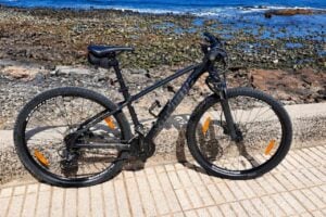 Mountain bike parked beside a rocky Atlantic coastline during a bike rental adventure in Tenerife.