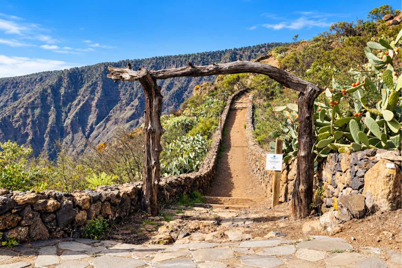 Hiking trail between volcanic cliffs and stone walls in El Hierro
