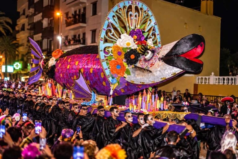 The giant decorated sardine of the Entierro de la Sardina carried through Santa Cruz at night by mourners in black with painted skull faces