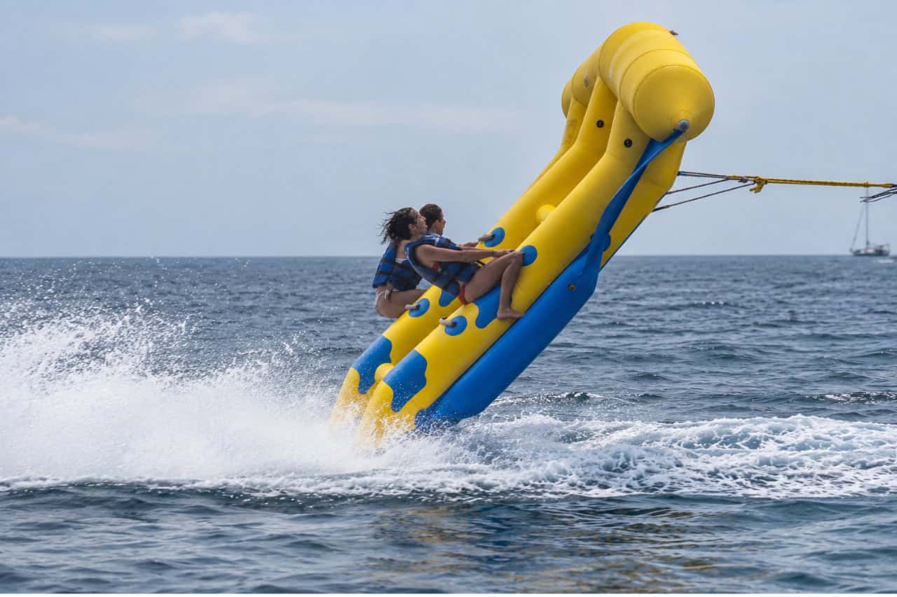 Three riders holding on to the Flying Fish as it rises above the sea in Tenerife