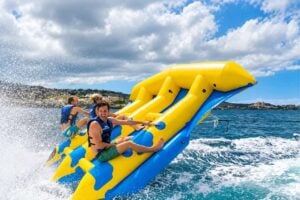 Riderne holder fast i en gult og blå Flying Fish-inflatable, mens den løfter sig over bølgerne under en højhastighedsoplevelse med vandsport i Playa de las Americas, Tenerife.