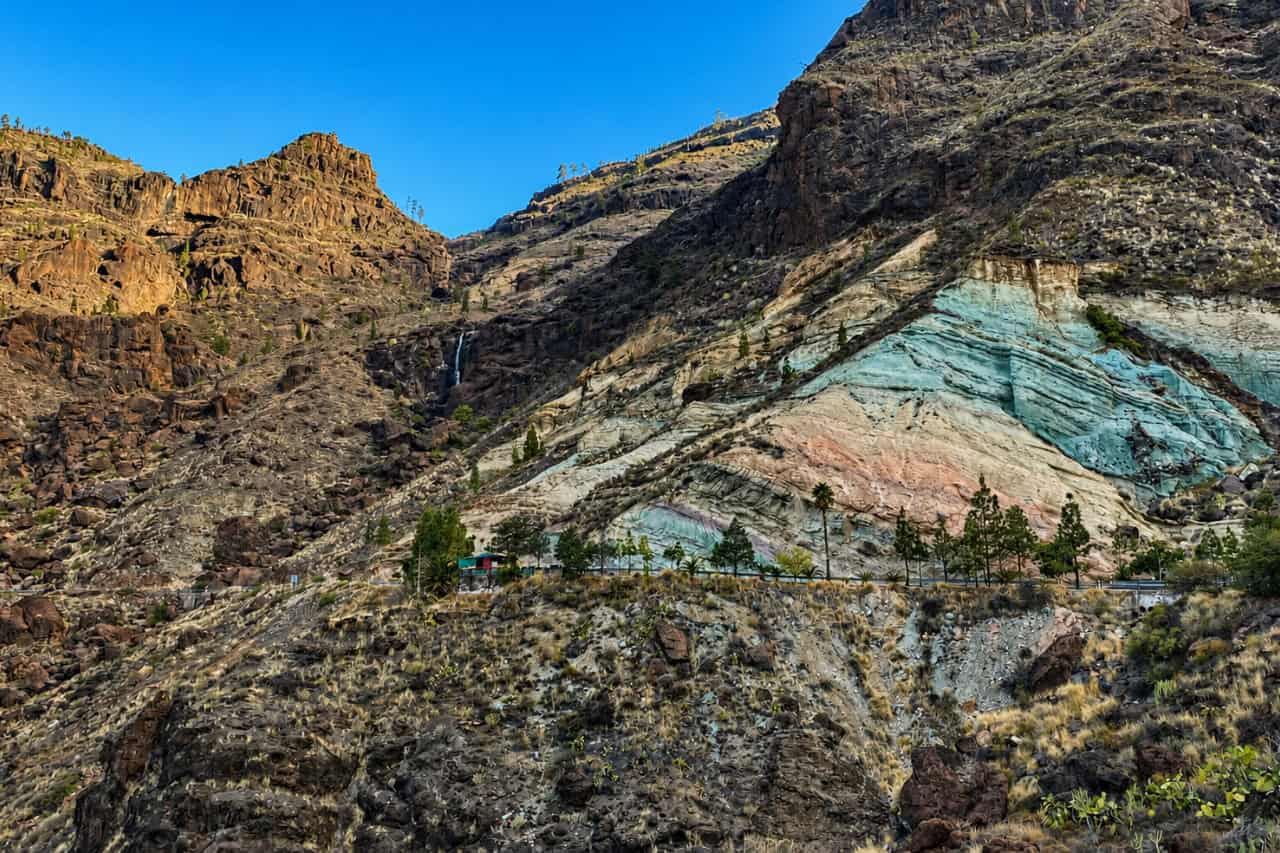 Striking green, turquoise and ochre rock layers at Los Azulejos, surrounded by the rugged volcanic mountains of Gran Canaria.