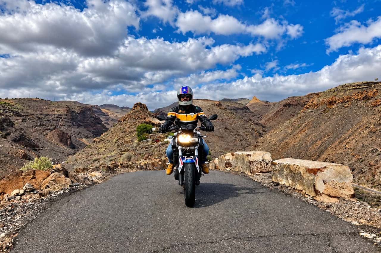 Motorcyclist riding through Tenerife’s rugged volcanic landscape on a scenic mountain road.