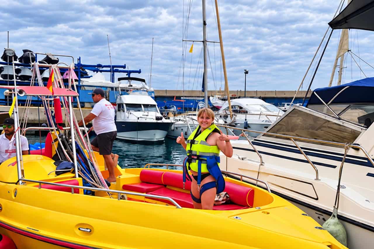 Guest in a life jacket on the yellow parasailing boat at Puerto Colon, Tenerife