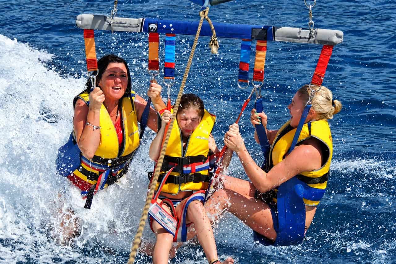 Three guests on a parasailing flight dipping their feet in the Atlantic off Tenerife
