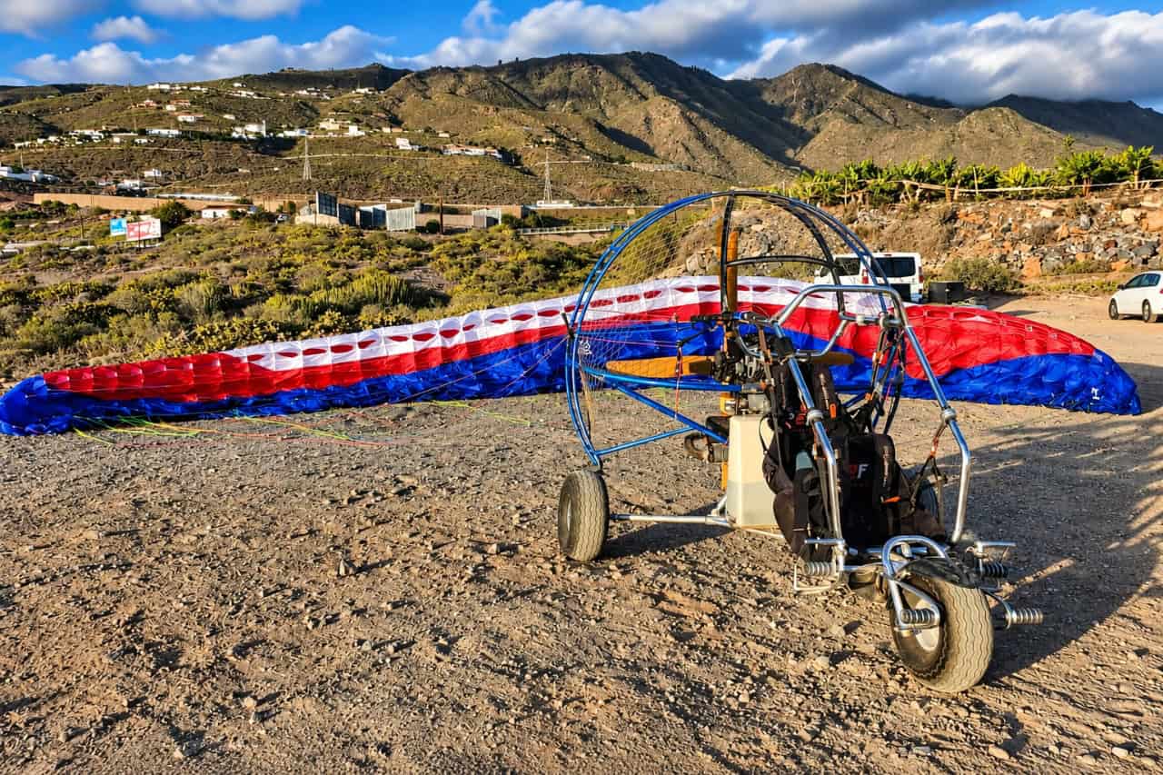 Paratrike with its red, white and blue wing prepared on the ground before a scenic tandem flight in Tenerife.